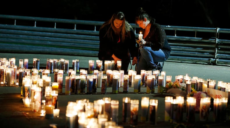 Meriah Calvert, left, of Roseburg, Ore., and an unidentified woman pray by candles spelling out the initials for Umpqua Community College after a candlelight vigil Thursday, Oct. 1, 2015, in Roseburg, Ore. A man opened fire at the school before dying in a shootout with police. (AP Photo/John Locher)
