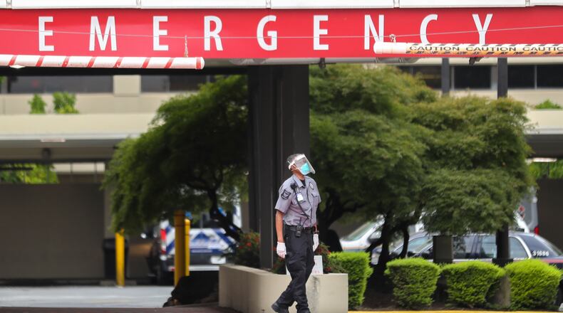A security guard waits at the emergency entrance at Wellstar Atlanta Medical Center on Boulevard in Atlanta on Wednesday. In five of Georgia's 14 hospital regions, ICUs were over 100 percent capacity, as of Tuesday night. That left patients across the state waiting in Emergency Departments for a critical-care bed, or remaining in rural hospitals even though they needed to be transferred for higher-level care. Meanwhile, ambulance drivers routinely waited for hours outside hospitals, tending to their patients until space opened up for them to be transported inside. (John Spink / John.Spink@ajc.com)