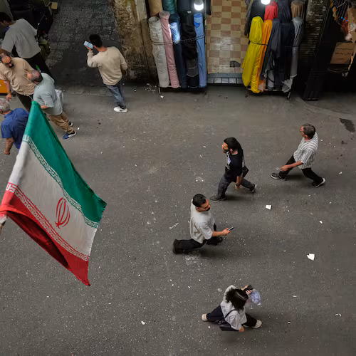 People walk as Iranian flags hang in the Grand Bazaar in Tehran, Sunday, May 3, 2026. (AP Photo/Vahid Salemi)