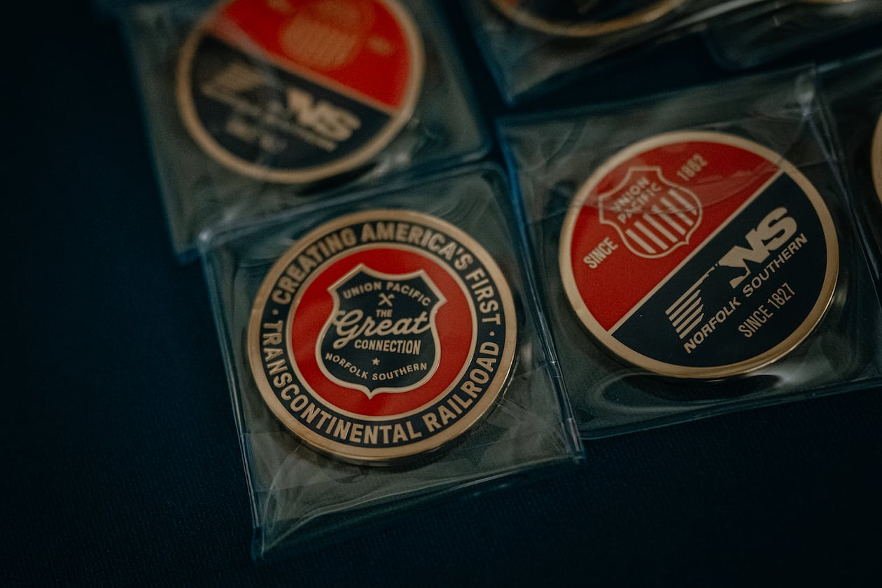 Collector coins labeled “The Great Connection,” referring to the proposed merger between Union Pacific and Norfolk Southern, sit on a table at Railway Age’s Next Generation Freight Rail conference where the two companies were presenting at the Union League Club of Chicago on March 10, 2026 in Chicago. (Jamie Kelter Davis for the AJC)