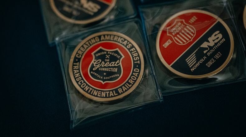 Collector coins labeled “The Great Connection,” referring to the proposed merger between Union Pacific and Norfolk Southern, sit on a table at Railway Age’s Next Generation Freight Rail conference where the two companies were presenting at the Union League Club of Chicago on March 10, 2026 in Chicago. (Jamie Kelter Davis for the AJC)