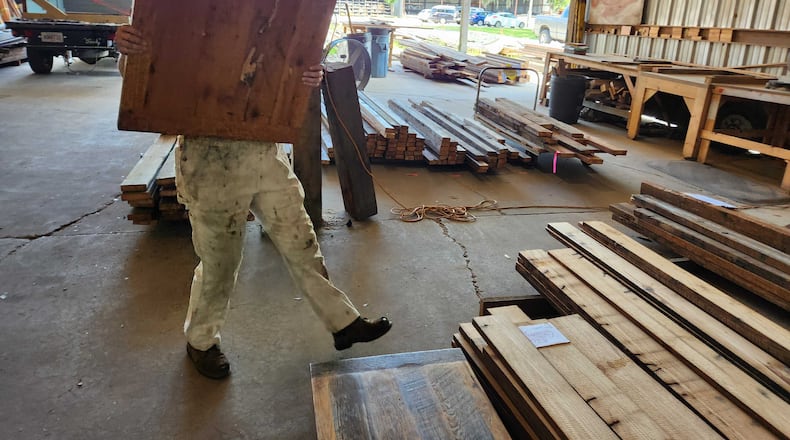 Re:Purpose Savannah salvage manager Jordan Lynch carries a donated wood panel into the organization's warehouse, where they get salvaged materials like this ready for reuse in other projects. (Photo Courtesy of Emily Jones/WABE)