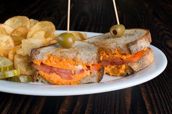 Peach & The Porkchop’s grilled pimento cheese sandwich is served with tomato on sourdough bread, alongside house-made chips. / Photo credit: George Miko Photography