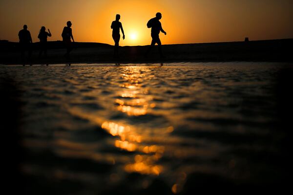 FILE - Tourists walk on the Giftun Island beach as the sun sets over the Red Sea in Hurghada, Egypt, Thursday Aug. 20, 2015. (AP Photo/Hassan Ammar, File)