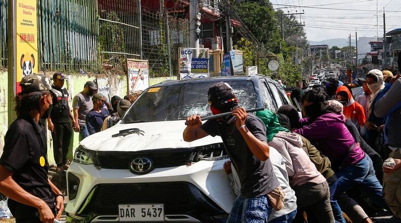 A group attacks a vehicle from an opposing group outside a school used as a polling center during the Bangsamoro Autonomous Region in Muslim Mindanao parliamentary elections in Cotabato city, southern Philippines, Monday, Sept. 14, 2026. (AP Photo)