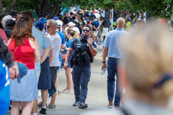 A police officer patrols the line outside FIFA Fan Fest at Centennial Olympic Park in Atlanta before a viewing of the Spain versus France World Cup game on July 14, 2026. (Arvin Temkar/AJC)
