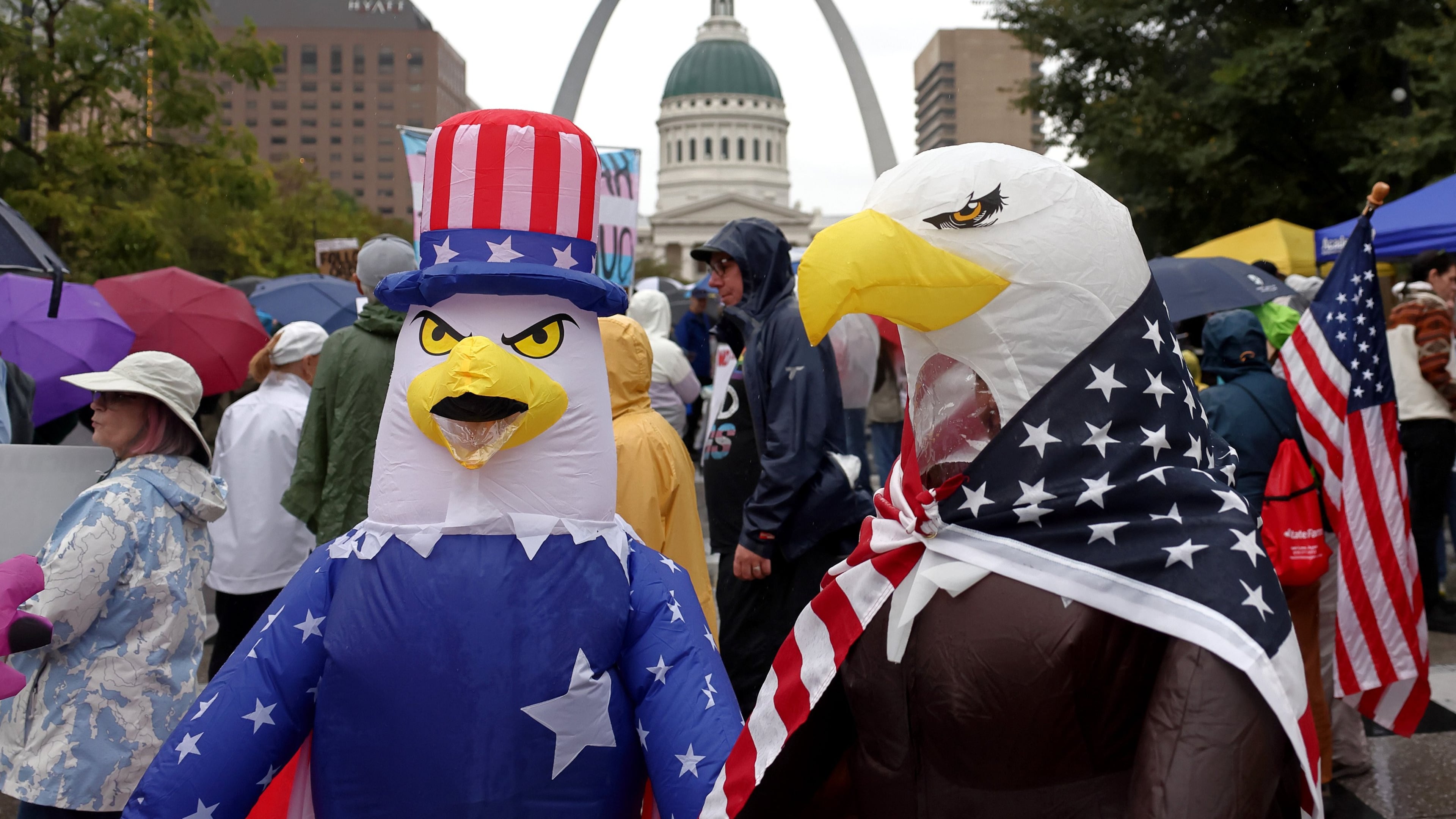 Demonstrators wearing inflatable bald eagle costumes gather in Kiener Plaza during the "No Kings" protest in St. Louis, with the Gateway Arch in the background, on Saturday, Oct. 18, 2025. (David Carson/St. Louis Post-Dispatch via AP)