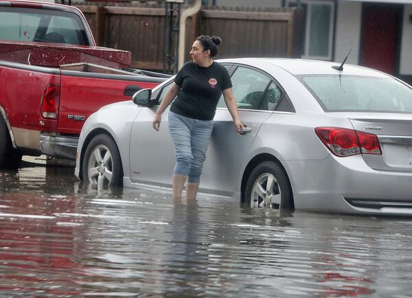 A woman attempts to open the door of her vehicle after a downpour on Thursday, March 27, 2025, in McAllen, Texas. (Joel Martinez /The Monitor via AP)