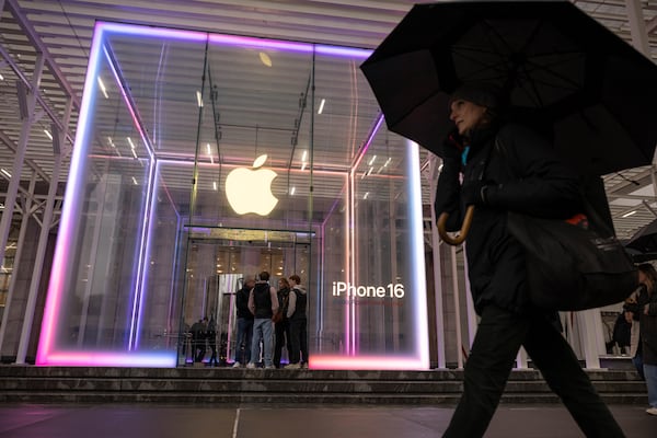 A person carrying an umbrella walks past the Apple Store on the 5th Avenue, Monday, April 7, 2025, in New York. (AP Photo/Yuki Iwamura)