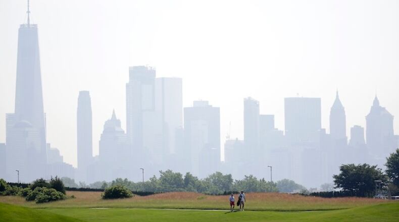 -PLEASE HOLD FOR STORY BY TOM CANAVAN- In a photo taken Tuesday, June 13, 2017, in Jersey City, N.J., a golfer and his caddie walk along the fairway on the No. 1 hole with the New York City skyline as a backdrop at Liberty National Golf Club. The club will host the 2017 Presidents Cup in late September. (AP Photo/Julio Cortez)