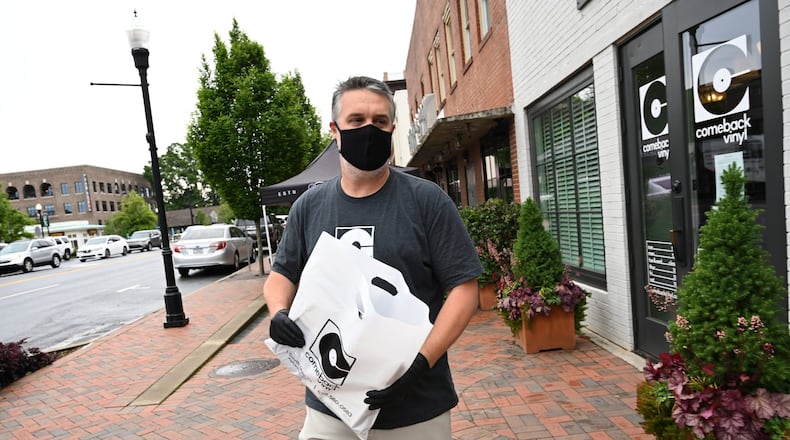 Connor Herrington makes a curbside delivery of albums to a customer outside Comeback Vinyl, a new and used independent record store in downtown Alpharetta, on Friday, May 8, 2020. Retail has suffered during the pandemic, and record shops are no exception. Some posted GoFundMe campaigns to help them stay afloat and pay employees, some offered mail order and curbside pickup and now a few are slowly reopening their doors to customers. (Hyosub Shin / Hyosub.Shin@ajc.com)