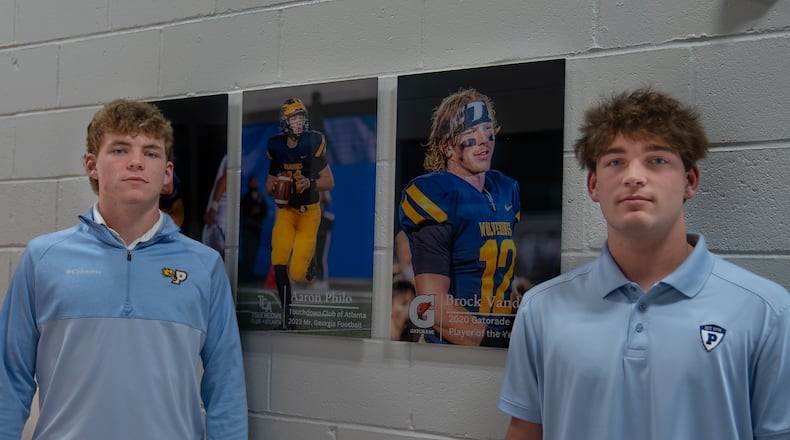 Sophomore Ben Musser, left, and senior Jake Bobo, right, stand next to photos of former Prince Avenue quarterbacks Aaron Philo and Brock Vandagriff.
