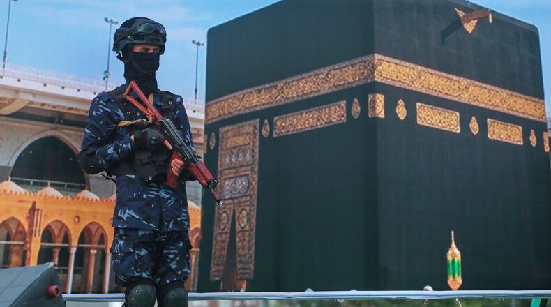 A soldier from Yemen's Houthi rebels stands in front of a giant banner of the Kaaba, during a rally to protest Saudi Arabia's accusation that the Houthis targeted Islam's holiest site in Sanaa, Yemen, Friday, Sept. 18, 2026. (AP Photo/Osamah Abdulrahman)