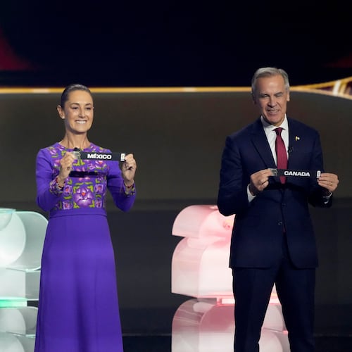 President Donald Trump, Mexican President Claudia Sheinbaum, and Canadian Prime Minister Mark Carney holds their countries' name during the draw for the 2026 soccer World Cup at the Kennedy Center in Washington, Friday, Dec. 5, 2025. (AP Photo/Chris Carlson)