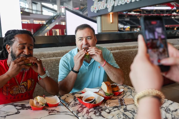 Food content creator Justin Brown, known as the Real Food Stalker (left), and AJC reporter Henry Hollis try some of the new food options at Mercedes-Benz Stadium in Atlanta on Sept. 15, 2026. (Arvin Temkar/AJC)