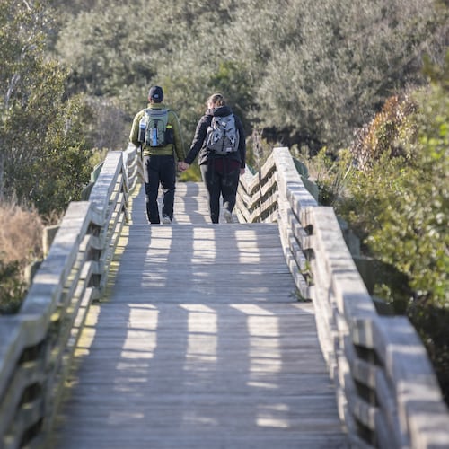 A couple takes the Sea Camp boardwalk as they spend their wedding anniversary enjoying the national seashore in Cumberland Island. The island is big enough to welcome both the public visitor and the private property holder to enjoy its beauty, guest columnist Sam Candler writes. (Stephen B. Morton/AJC 2022)