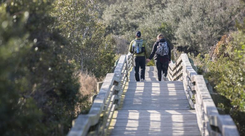 A couple takes the Sea Camp boardwalk as they spend their wedding anniversary enjoying the national seashore in Cumberland Island. The island is big enough to welcome both the public visitor and the private property holder to enjoy its beauty, guest columnist Sam Candler writes. (Stephen B. Morton/AJC 2022)
