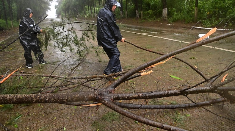 In this photo released by Xinhua News Agency, workers clear up a fallen tree along a road in Jiangping town, Dongxing of Fangchenggang, south China's Guangxi Zhuang Autonomous Region on Saturday, July 4, 2026, after a severe weather system was affecting the area. (Lu Boan/Xinhua via AP)