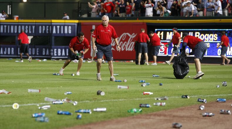 Atlanta Braves ground crew members clean trash off the field after fans littered the area protesting an infield fly rule call on Andrelton Simmons in the eighth inning of the National League wild card game against the St. Louis Cardinals at Turner Field in Atlanta on Friday, Oct. 5, 2012. CURTIS COMPTON / CCOMPTON@AJC.COM
