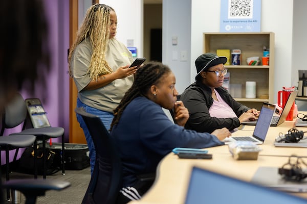 Participants Kiandra Peart (center) and Sheniya Weems (right) work as Jihan Johnston-McGlotten (standing), managing director of Beyond Code Centers, assists during the AI Fundamentals for Digital Natives program put on by Beyond Code Collective at Advanced Technology Development Center at Tech Square in Atlanta on June 5, 2026. (Arvin Temkar/AJC)