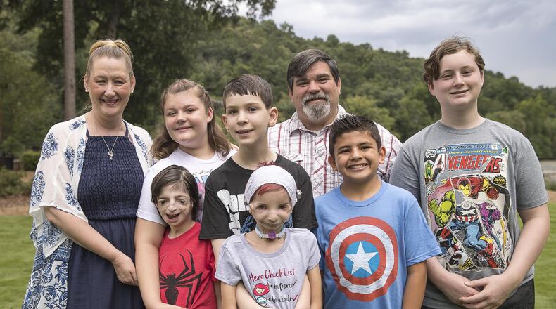 The Delaney family poses for a recent portrait outside one of their older sons’ apartment complex in Atlanta, where they stayed to keep them close to a scheduled doctor’s appointment. Parents Amy and Derron with their children: (top row; from left) Grace, Avery, Jeremiah, Logan, (bottom row; from left) Malachi and Lexie. ALYSSA POINTER / ALYSSA.POINTER@AJC.COM