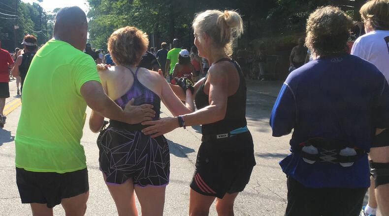 A runner gets some help to make it the final stretch down 10th Street during the AJC Peachtree Road Race on Monday morning July 4, 2016. Ben Gray / bgray@ajc.com