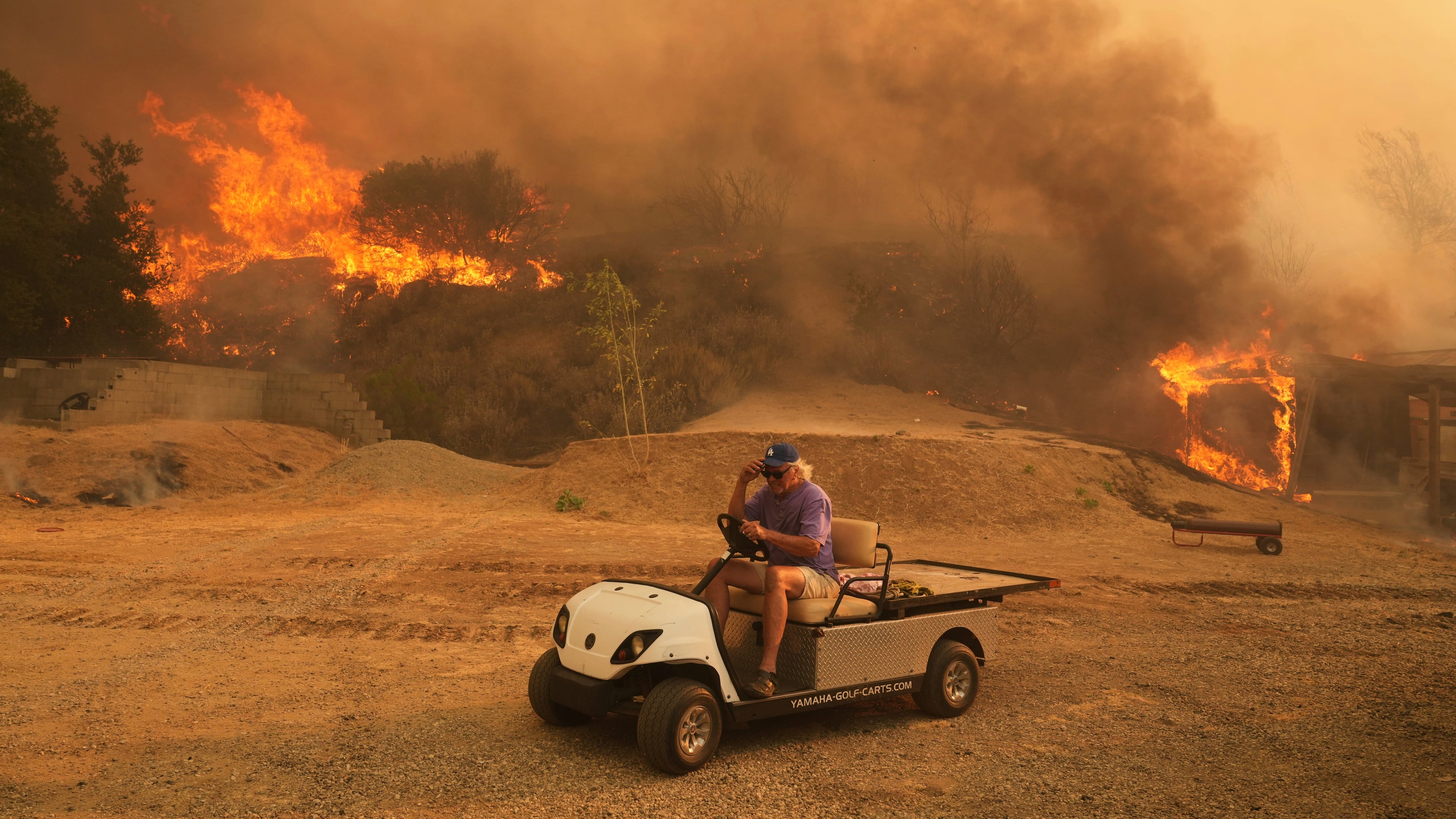 FILE - A resident rides a golf cart as he exits his property while the Canyon Fire burns on Aug. 7, 2025, in Hasley Canyon, Calif. (AP Photo/Marcio Jose Sanchez, File)