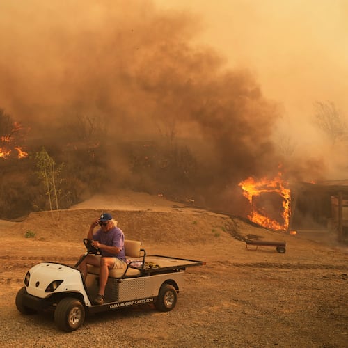 FILE - A resident rides a golf cart as he exits his property while the Canyon Fire burns on Aug. 7, 2025, in Hasley Canyon, Calif. (AP Photo/Marcio Jose Sanchez, File)