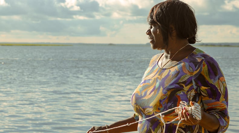 Chef Sallie Ann Robinson expertly throws her crab net into the water, blending skill with heritage as she gathers fresh crabs for her signature dish, Ol' 'Fuskie Fried Crab Rice. (Adriana Iris Boatwright for the Atlanta Journal-Constitution)