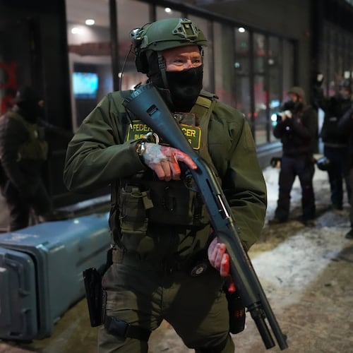 A federal agent stands guard near a hotel during a noise demonstration protest in response to federal immigration enforcement operations in the city Sunday, Jan. 25, 2026, in Minneapolis. (AP Photo/Adam Gray)