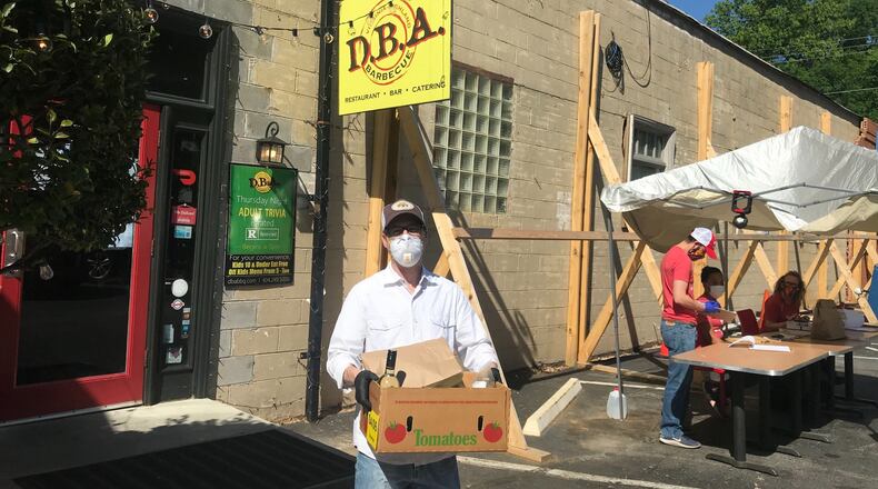D.B.A. Barbecue owner Matt Coggin carries an order for pickup. “We ll get through it,” Coggin said of keeping the business afloat during the current pandemic. LIGAYA FIGUERAS / LIGAYA.FIGUERAS@AJC.COM
