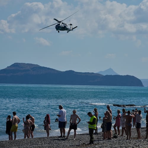 Tourists from nearby hotels watch a military helicopter fly overhead during Medusa 15, a multinational military exercise led by Greece and Egypt, at Maleme on the Greek island of Crete, Friday, Sept. 18, 2026. (AP Photo/Thanassis Stavrakis)