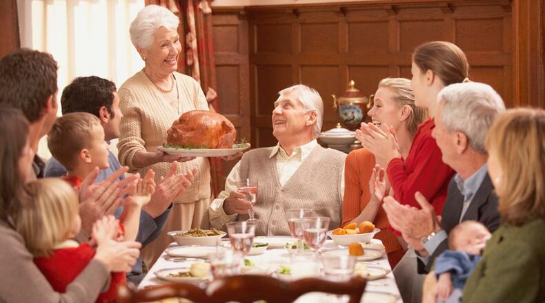 File photo - Grandmother presenting turkey to her family at the dinner table