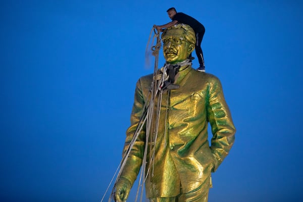 FILE - A man climbs to tie a rope around the head of a large statue of Sheikh Mujibur Rahman, father of Bangladesh leader Sheikh Hasina, as protesters try to bring it down after she resigned as Prime Minister, in Dhaka, Bangladesh, on Aug. 5, 2024. (AP Photo/Rajib Dhar, File)