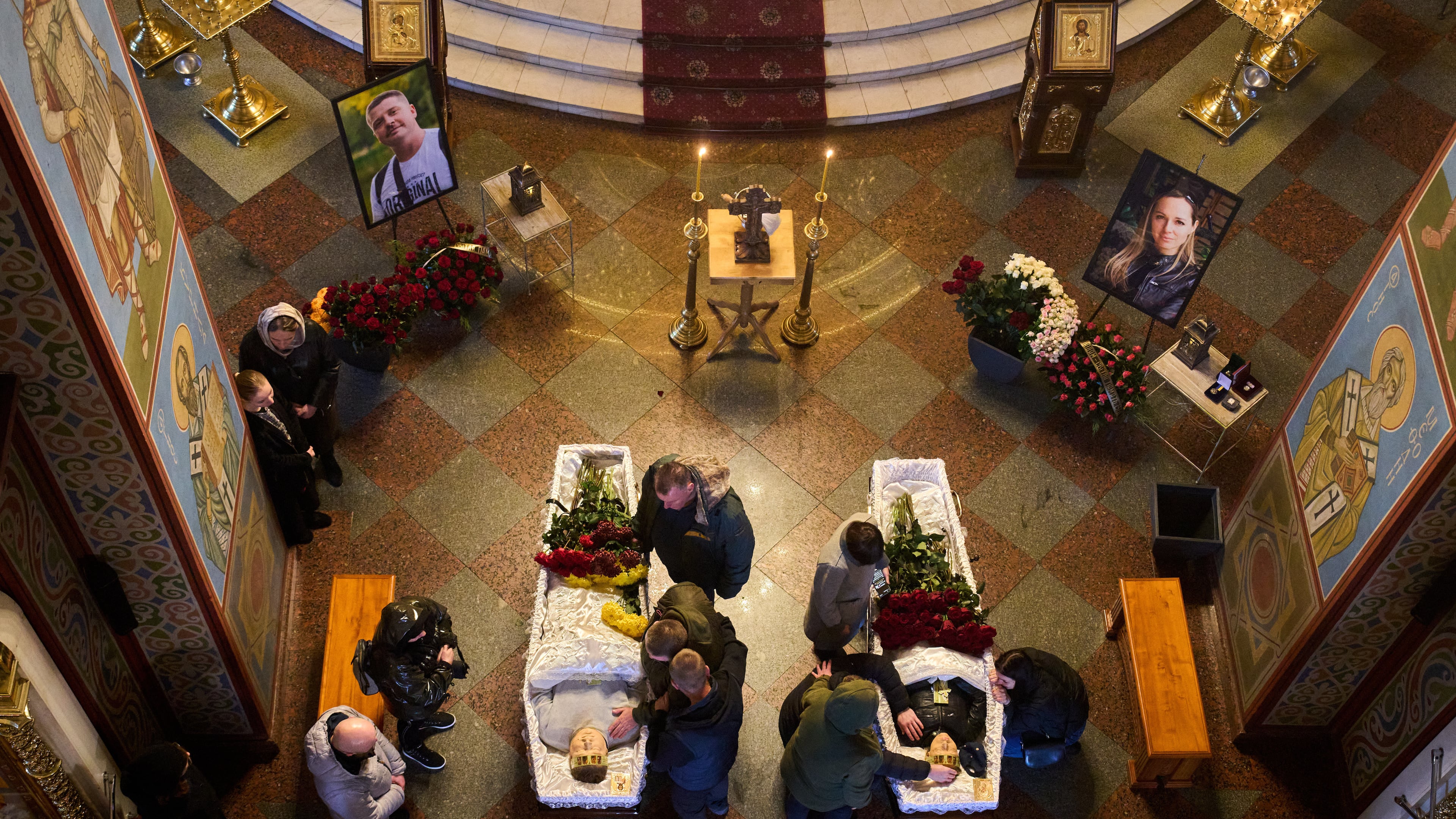 Relatives, colleagues and friends of two Ukrainian 43-year-old journalists Olena Hubanova, who worked under the pseudonym Alyona Gramova, and cameraman Yevhen Karmazin, who were killed on Thursday, Oct. 23, mourn over their coffins during a funeral service at St. Michael Monastery in Kyiv, Ukraine, Monday, Oct. 27, 2025. (AP Photo/Efrem Lukatsky)