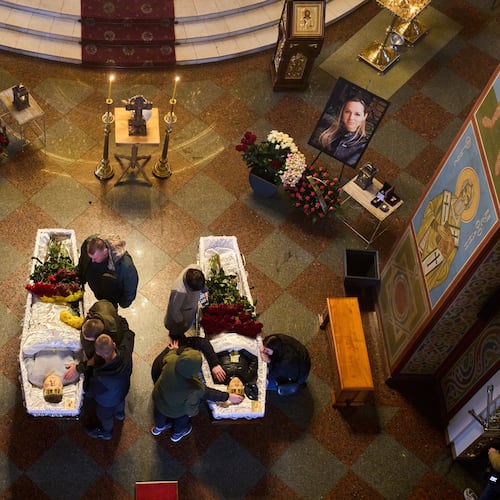 Relatives, colleagues and friends of two Ukrainian 43-year-old journalists Olena Hubanova, who worked under the pseudonym Alyona Gramova, and cameraman Yevhen Karmazin, who were killed on Thursday, Oct. 23, mourn over their coffins during a funeral service at St. Michael Monastery in Kyiv, Ukraine, Monday, Oct. 27, 2025. (AP Photo/Efrem Lukatsky)