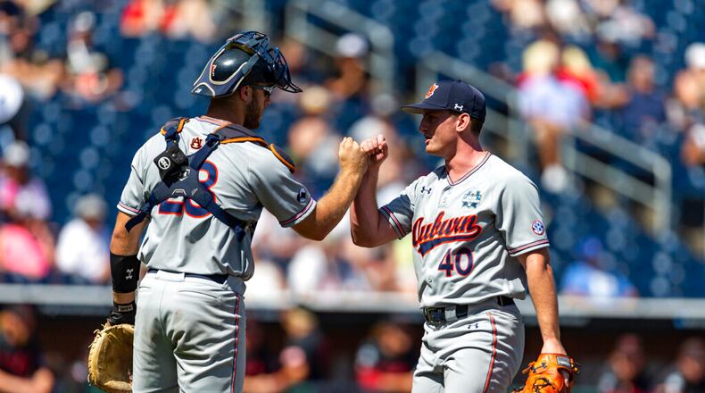 Auburn pitcher Blake Burkhalter (40) and catcher Nate LaRue (28) fist bump after the seventh inning against Stanford in an NCAA College World Series baseball game Monday, June 20, 2022, in Omaha, Neb. (AP Photo/John Peterson)