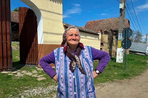 Zoica Roth, 83, stands outside her house in the village of Saschiz, in Romania's central Transylvania region, Friday, April 25, 2025. (AP Photo/Stephen McGrath)