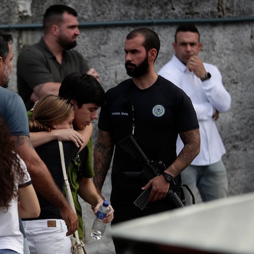 People comfort each other near the site where two helicopters reportedly collided in midair and crashed into a car dealership parking lot in Rio de Janeiro, Brazil, Sunday, June 14, 2026. (AP Photo/Bruna Prado)