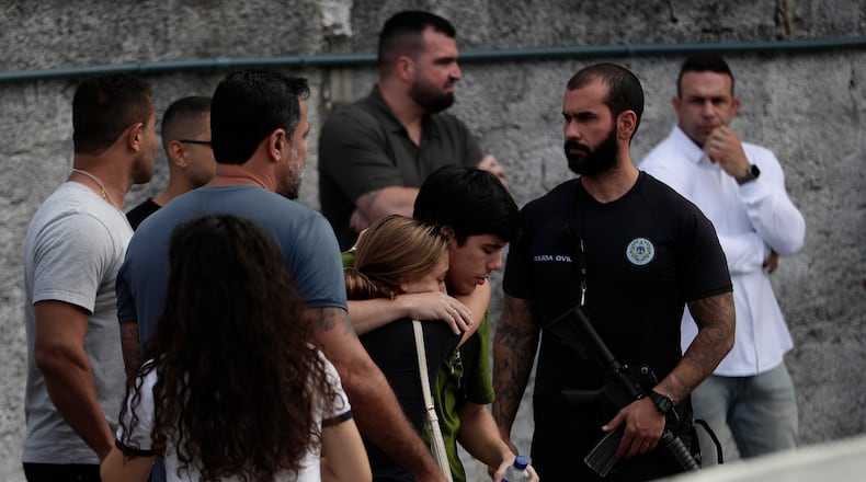 People comfort each other near the site where two helicopters reportedly collided in midair and crashed into a car dealership parking lot in Rio de Janeiro, Brazil, Sunday, June 14, 2026. (AP Photo/Bruna Prado)