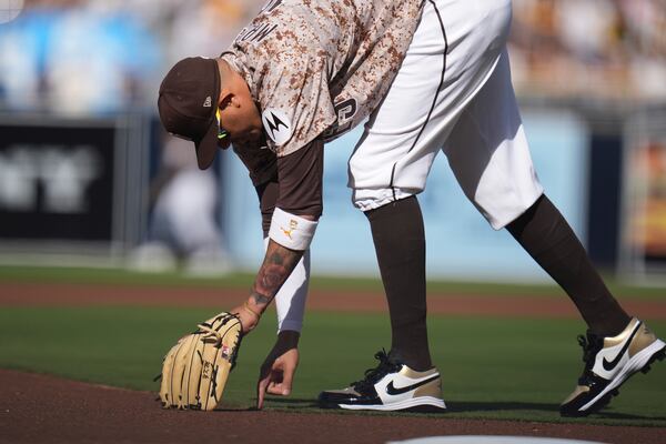 San Diego Padres third baseman Manny Machado draws in the infield dirt before the start of a baseball game against the Atlanta Braves, Sunday, March 30, 2025, in San Diego. (AP Photo/Gregory Bull)