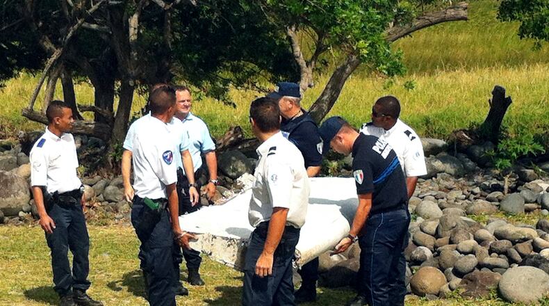 Police and gendarmes carry a piece of debris from an unidentified aircraft found in the coastal area of Saint-Andre de la Reunion, in the east of the French Indian Ocean island of La Reunion, on July 29, 2015. The two-metre-long debris, which appears to be a piece of a wing, was found by employees of an association cleaning the area and handed over to the air transport brigade of the French gendarmerie (BGTA), who have opened an investigation. An air safety expert did not exclude it could be a part of the Malaysia Airlines flight MH370, which went missing in the Indian Ocean on March 8, 2014. (Photo: YANNICK PITOU/AFP/Getty Images)