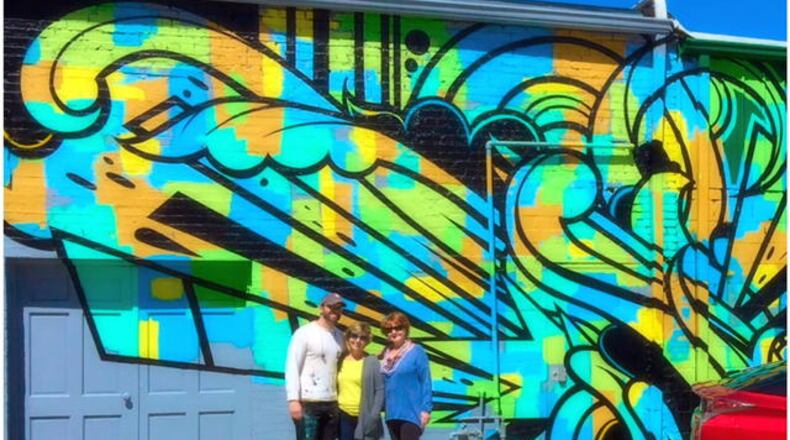 Artist Peter Ferrari completed his mural “Verb" last month on Norcross' Skin Alley. He is shown here with Norcross Public Arts Commission members Deb Harris and Cindy Flynn. (Credit: Norcross Public Arts Commission)