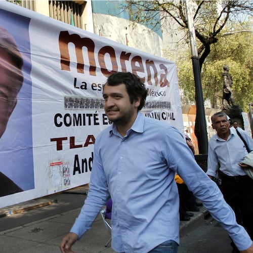 FILE - Andres Lopez Beltran, center, walks past a banner featuring an image of his father, Andres Manuel Lopez Obrador, in Mexico City, Dec. 6, 2013. (AP Photo/Marco Ugarte, File)