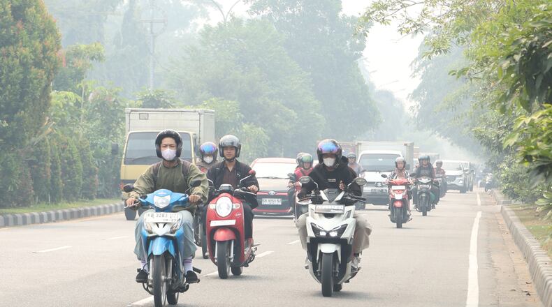 Motorists ride on a road as haze from wildfires blanket the city of Pontianak, West Kalimantan, Indonesia, Friday, Aug. 21, 2026. (AP Photo/Stefanus Taman)