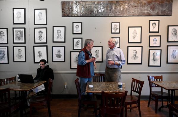 Allen Levi (right) talks with his portrait-artist friend Garry Pound at Fountain City Coffee, where Pound’s portraits are displayed on the walls. (Hyosub Shin/AJC)
