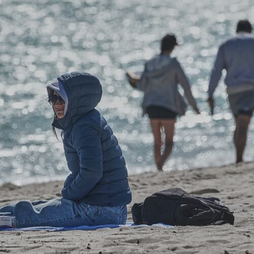 A bundled up Lucia Amato, of Argentina, sits on the shore while waiting for a friend in Miami Beach, Fla., Thursday, Jan. 29, 2026.A bundled up (AP Photo/Marta Lavandier)