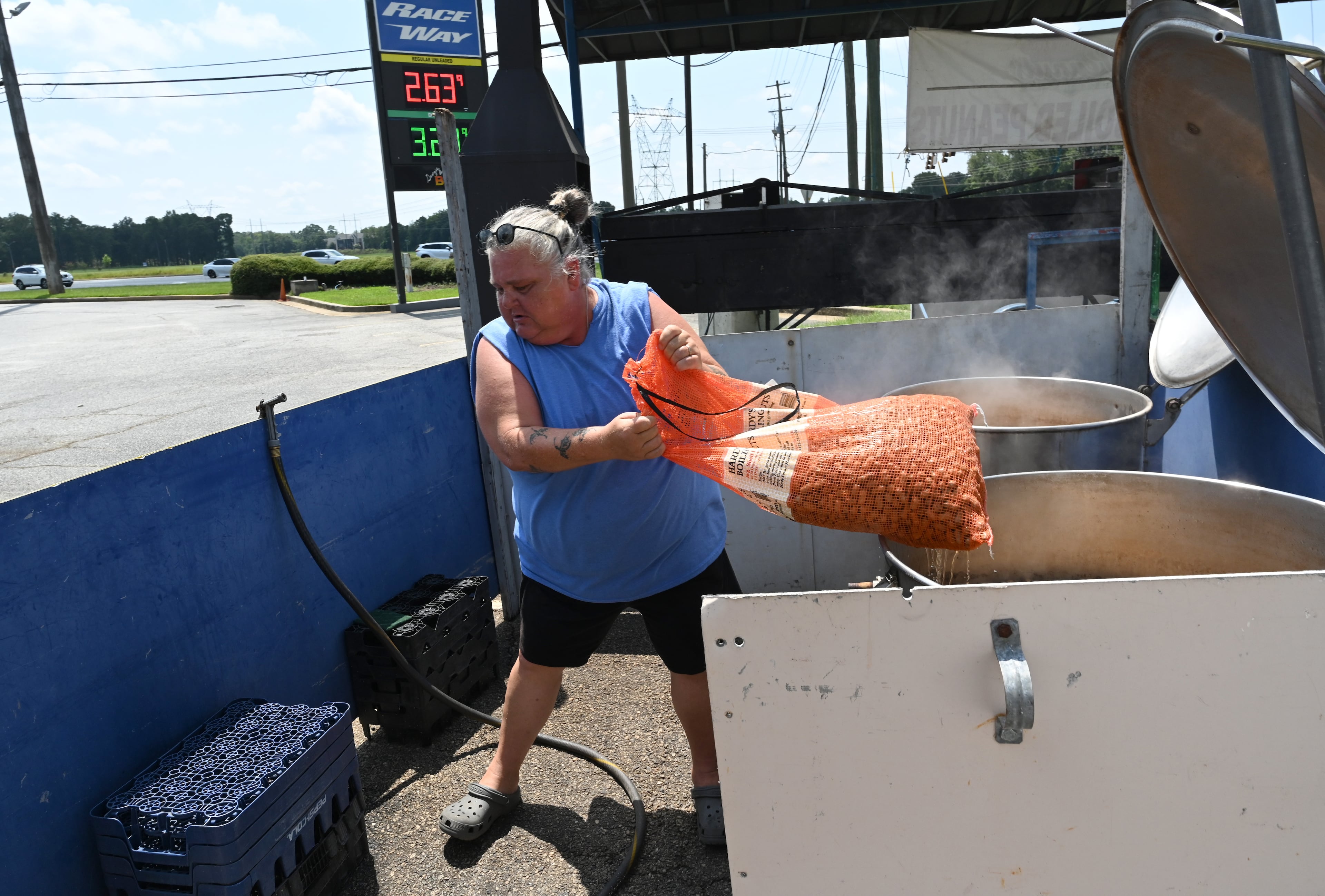 Timmi Moore, a peanut stand manager, pulls a bag of boil peanuts out of a steam kettle at a roadside stand in Warner Robins. (Hyosub Shin/AJC)
