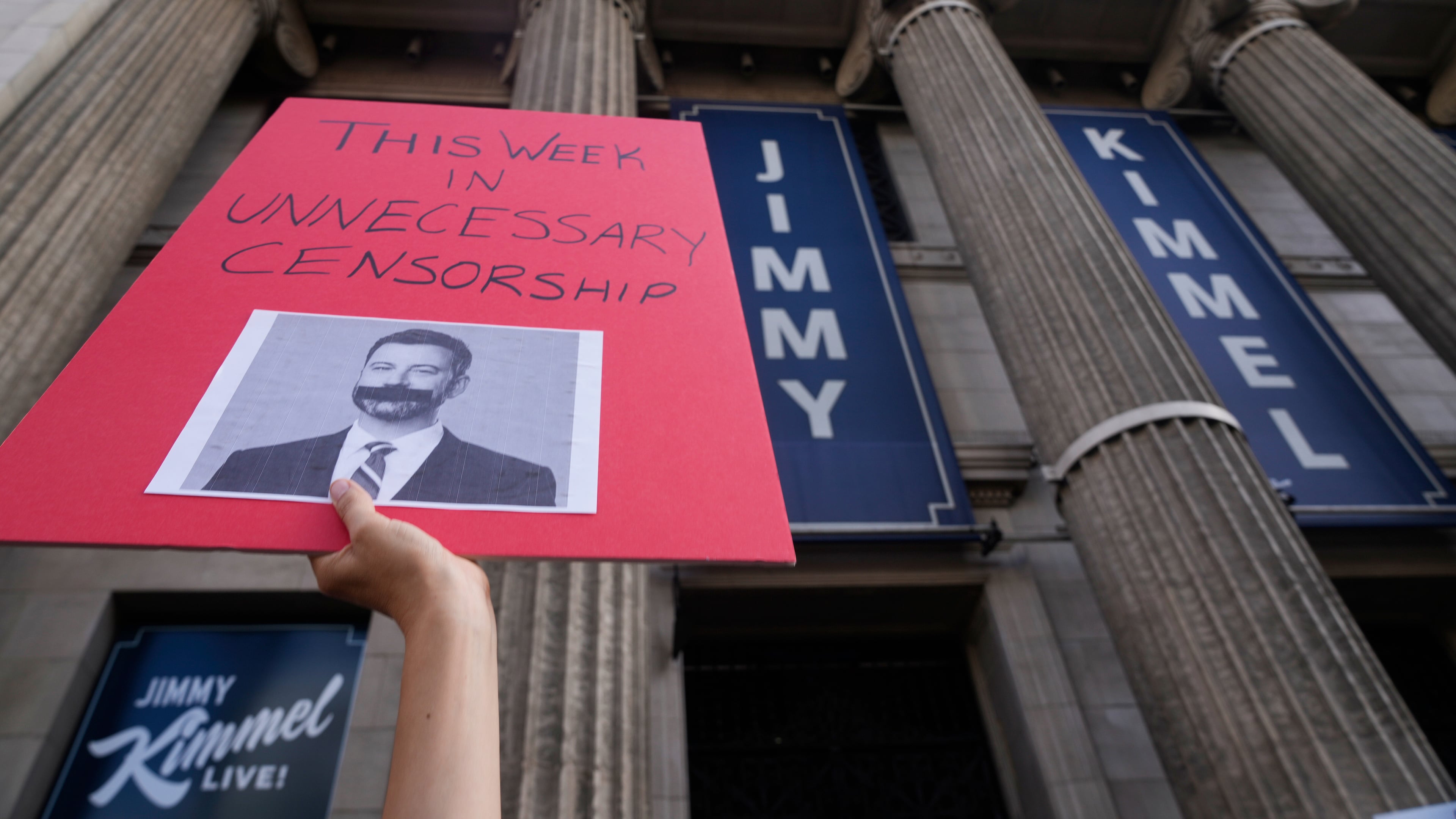 A demonstrator holds a sign outside El Capitan Entertainment Centre, where the late-night show "Jimmy Kimmel Live!" is staged on Thursday, Sept. 18, 2025, in Los Angeles. (AP Photo/Damian Dovarganes)