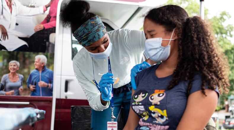 210719-Decatur -- Ashanti Booker, a registered nurse with the DeKalb County Board of Health, gives a Covid-19 vaccination to Raya High, 13, at a mobile clinic at Decatur High School on Monday afternoon, July 19, 2021. Ben Gray for the Atlanta Journal-Constitution